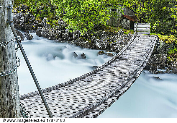 Norway  Vestland  Wooden bridge over river flowing in Hardangervidda range