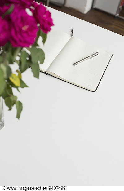 Notebook and roses on table