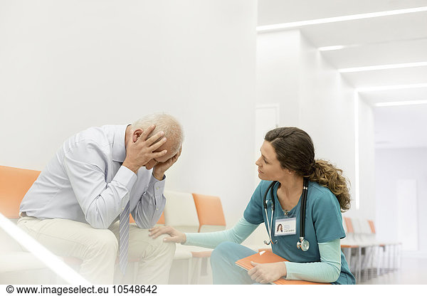 Nurse consoling upset man in clinic corridor