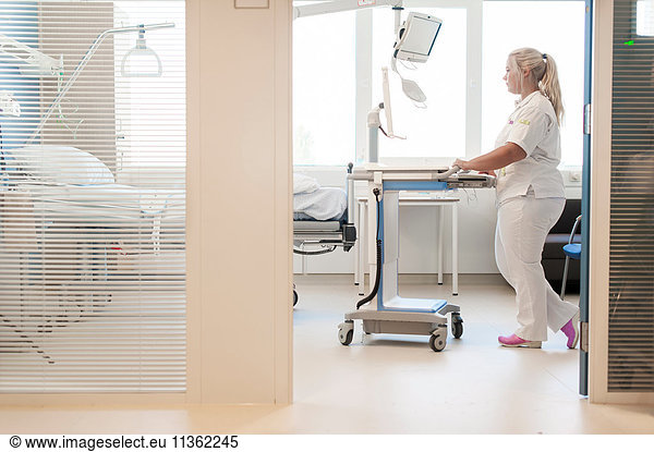 Nurse on hospital ward pushing trolley