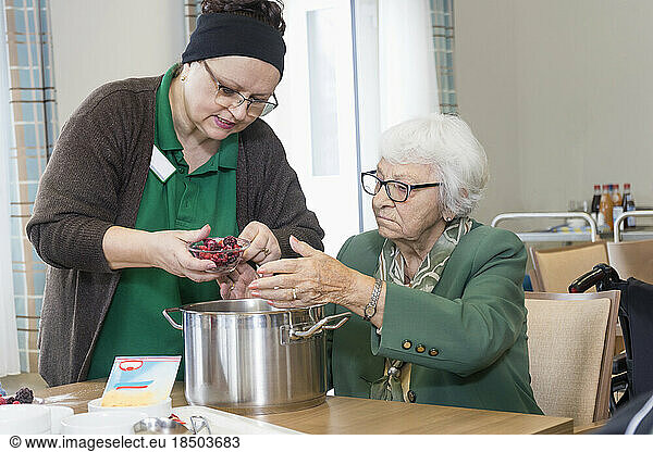 Nurse preparing food with senior woman in rest home