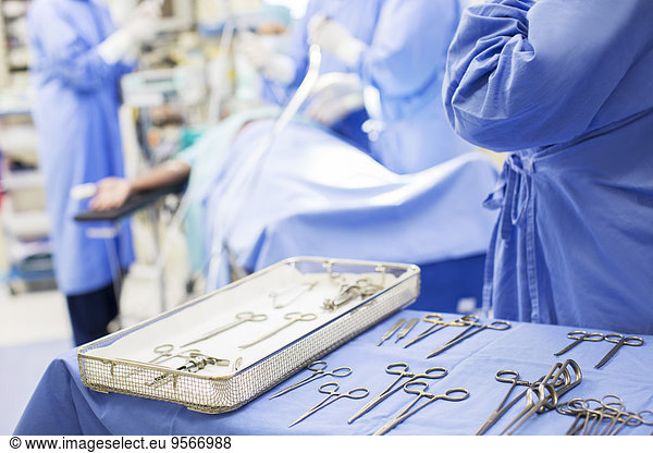 Nurse standing by tray with surgical tools in operating theater