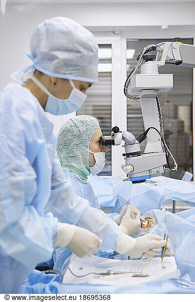 Nurse with doctor performing eye surgery in operating room