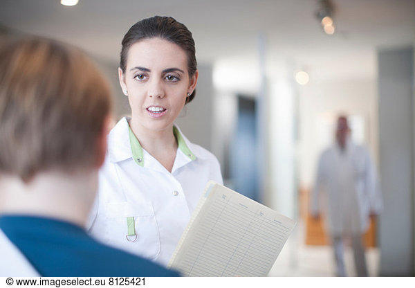 Nurse with patient and notes in reception