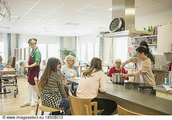 Nurse with senior women and girls preparing food at rest home