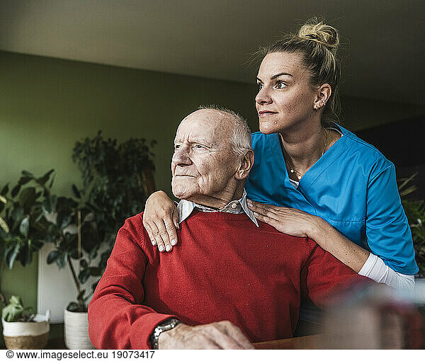 Nurse with thoughtful senior man sitting at home