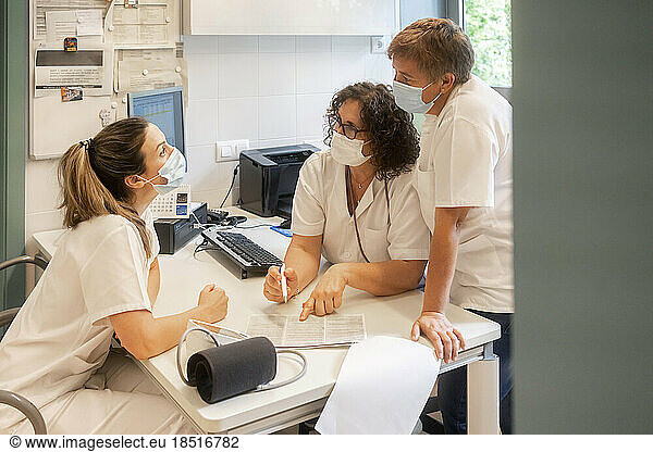 Nurses wearing protective face masks discussing together at clinic