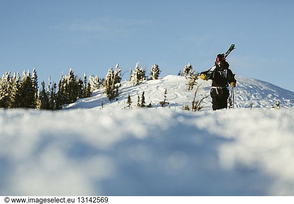 Oberflächenebenenbild eines Mannes mit Himmel  der auf einem schneebedeckten Berg gegen den Himmel läuft