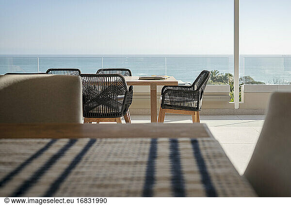 Ocean view behind dining table and chairs on sunny luxury patio