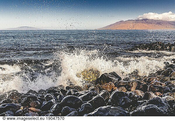 Ocean waves hitting rocks on sunny day in Wailea  Maui