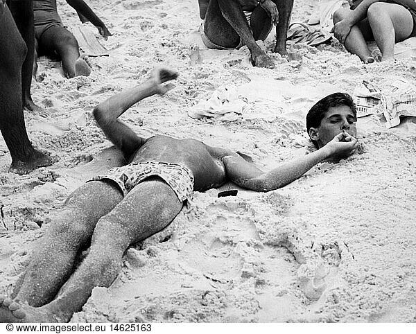oddity  beach  head beside body dug in the sand  smoking  Brazil  Rio de Janeiro  1960s