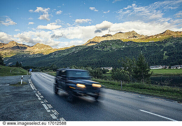 Off-Road car driving along asphalt road in Engadin valley