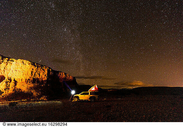 Off-road car in illuminated desert camp at night