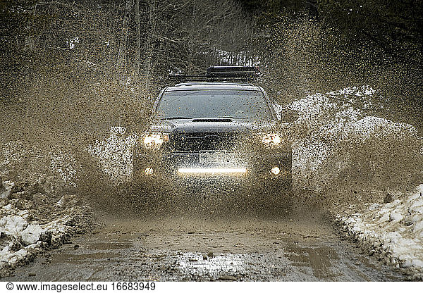 Off-road car splashing dirt on road during winter