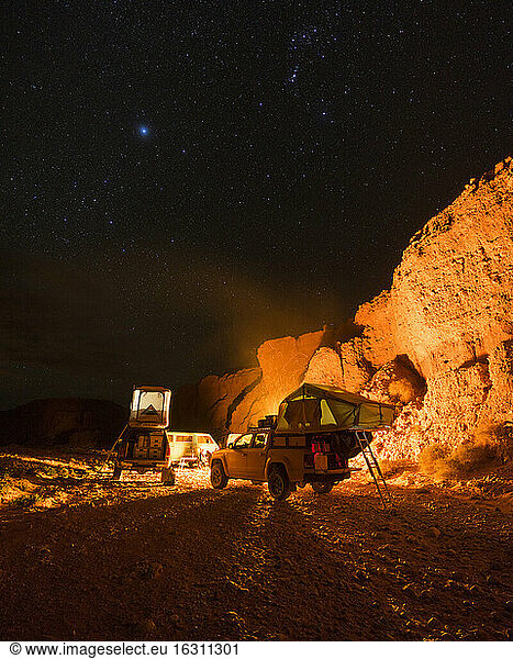 Off-road cars in illuminated desert camp at night