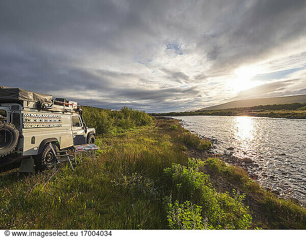 Off road vehicle against cloudy sky during sunset  Hraunfossar  Iceland