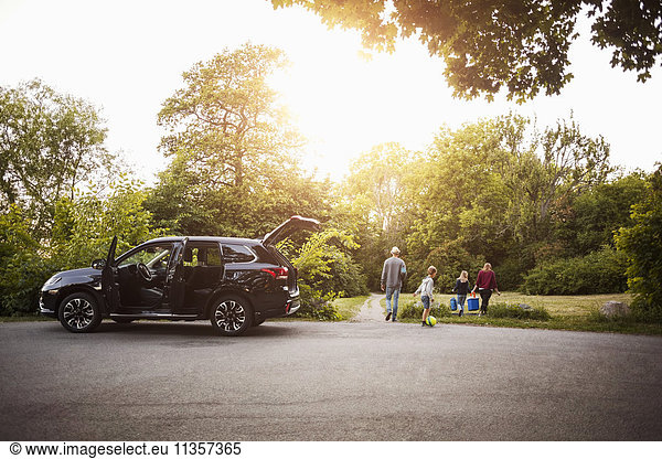 Offenes schwarzes Elektroauto mit Familienwanderung im Park