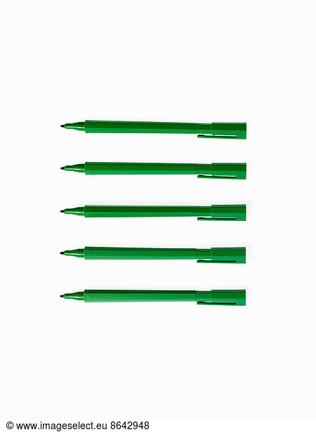 Office supplies. Green coloured pens  felt nibs and pen top cases  arranged in a row.