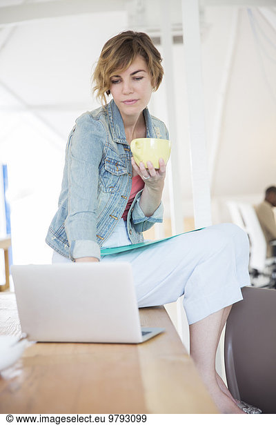 Office worker with coffee using laptop