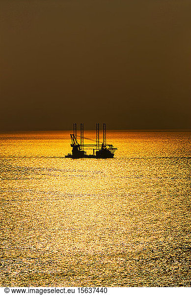 Offshore wind farm installation vessel sailing off in sea during sunset  West Coast  Scotland  UK