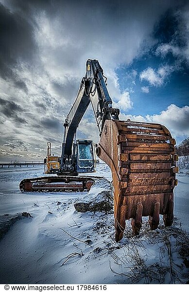 Old excavator with excavator bucket in winter. Road construction in snow. Lofoten islands  Norway. High dynamic range HDR image