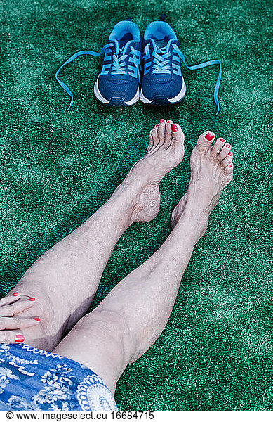 Old lady with toenails and red hand painted sitting on synthetic grass