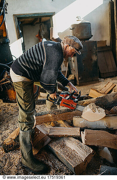 Old man cutting firewood at home.