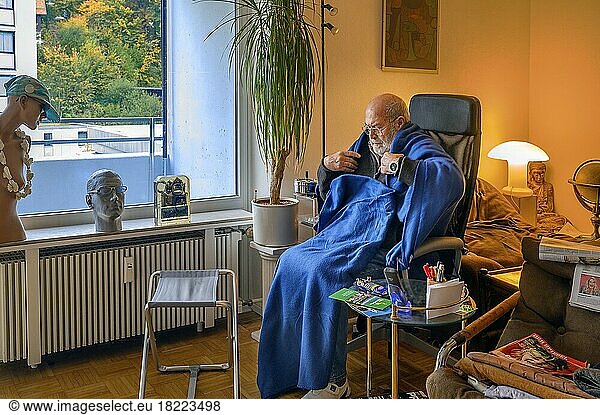 Old man wrapped in blankets  save energy  freeze because of Putin  save heating costs  low room temperature  Bavaria  Germany  Europe
