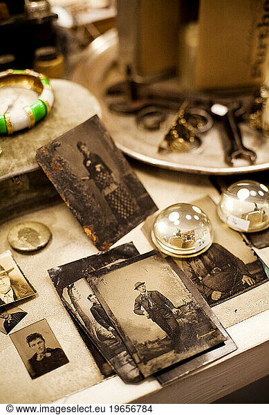 Old photographs sit on a shelf in an antique store.