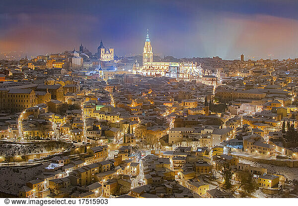 Old town with castle on snowy night and illuminated streets