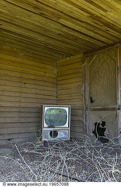 Old TV set on front porch of an abandoned homestead.