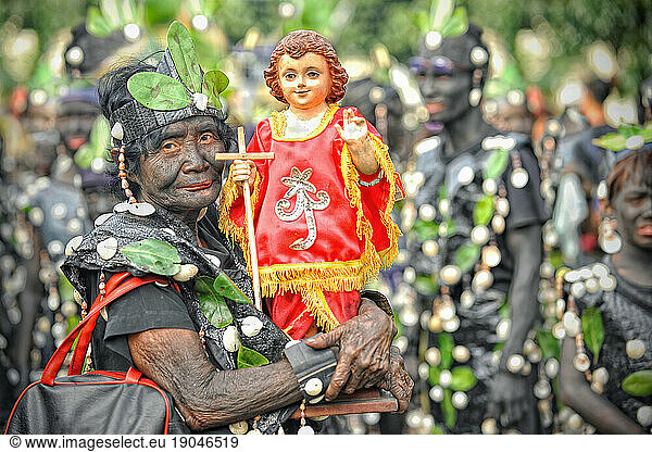 Old woman holding a Santo Nino figur at Ati Atihan festival.