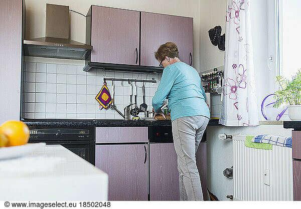 Old woman working with bread in the kitchen