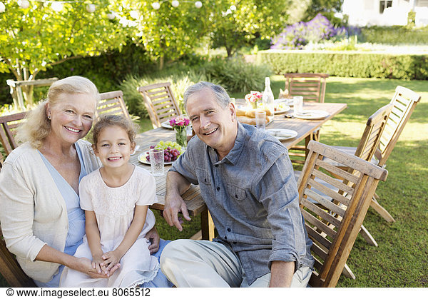 Older couple and granddaughter smiling outdoors