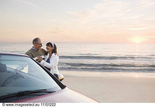 Older couple standing at car on beach