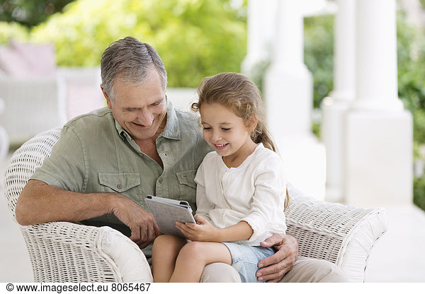 Older man and granddaughter using tablet computer