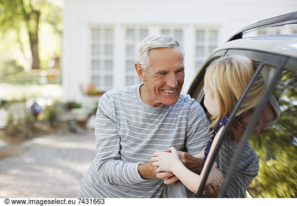 Older man greeting granddaughter in car window