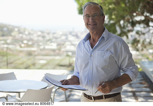 Older man reading papers outdoors