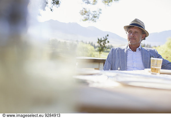 Older man sitting at outdoor dinning table