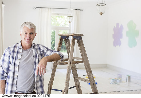Older man smiling near ladder in livingroom