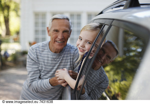 Older man talking to granddaughter in car window