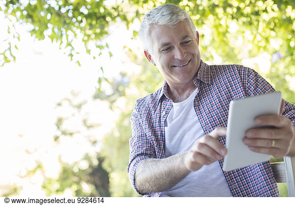 Older man using digital tablet outdoors