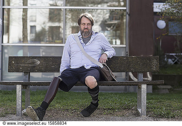 older man with prosthetic leg sitting on a bench