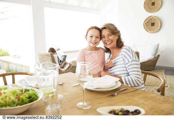 Older woman and granddaughter smiling at table