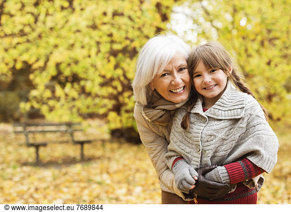 Older woman and granddaughter smiling in park