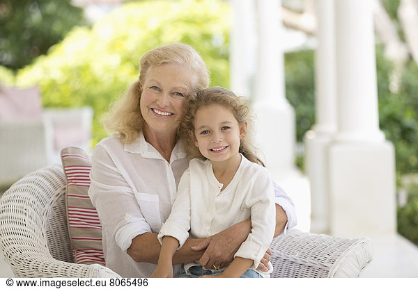 Older woman and granddaughter smiling on porch