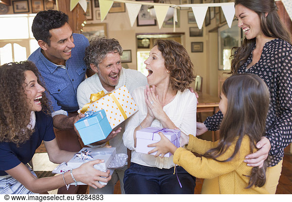 Older woman being given gift by family
