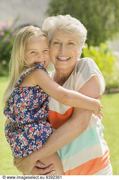 Older woman holding granddaughter in backyard
