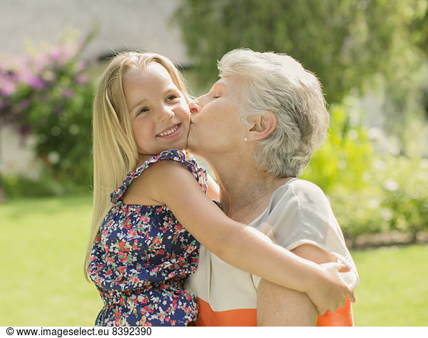 Older woman kissing granddaughter outdoors