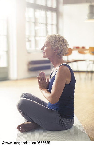 Older woman meditating on exercise mat